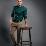 Picture of serious young man standing isolated over grey background. Looking at camera.